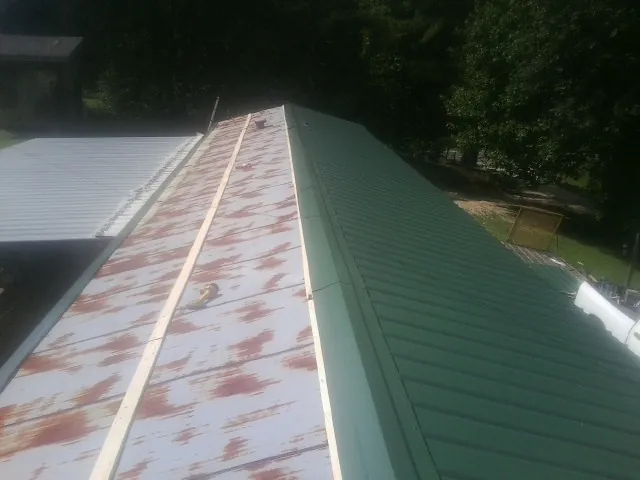Old rusted panels beside newly installed green metal roofing — Wind Damage Roof Repair by Roofing Brothers in North Canton