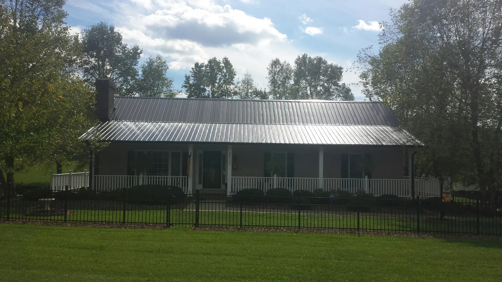 Gray metal roof on a brick ranch with a full width front porch — Gutter Guard Installation work by our crew in North Canton